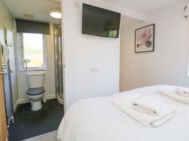 A bedroom with a bed and bathroom area at Dovedale Lodge Troutbeck Bridge