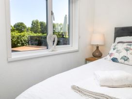A bedroom with a bed, lamp, and window at Dovedale Lodge Troutbeck Bridge