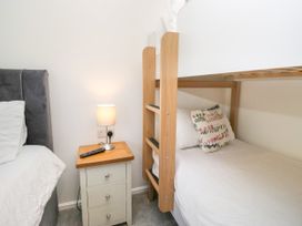 A bedroom with a bunk bed and a single bed at Dovedale Lodge in Troutbeck Bridge