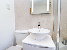 A bathroom with a sink, toilet, and shower at Dovedale Lodge, Troutbeck Bridge