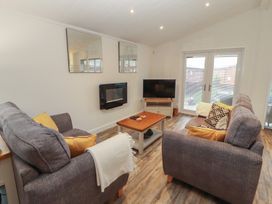 A living room with a coffee table and television at Dovedale Lodge in Bowness 70, White Cross Bay near Windermere