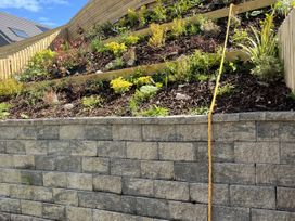 A garden with plants and a stone retaining wall at Golygfa Gele in Llanddulas