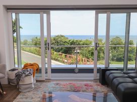 A living room with sliding glass doors opening to an ocean view at Golygfa Gele Llanddulas