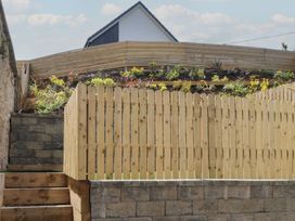 A garden with a wooden fence and a flowerbed at Golygfa Gele in Llanddulas