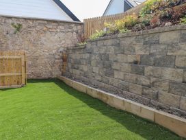 A garden with a stone wall and wooden fence at Golygfa Gele Llanddulas