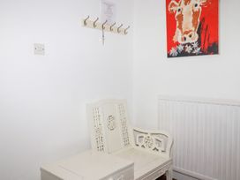A chair with coat hooks and a painting in the entryway at Rosemaddon in Crantock