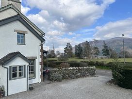 An outdoor view of a house with a gravel driveway and trees at Squirrel Cottage in Thornthwaite