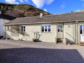 A single story house with two windows and a door on a gravel ground with hills in the background at Fox Howe in Thornthwaite