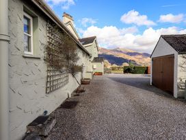 A gravel driveway between a house and a garage with hills in the background at Fox Howe in Thornthwaite