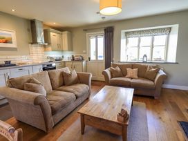 A living room with two sofas and a wooden coffee table next to a kitchen area at Fox Howe in Thornthwaite