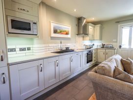 A kitchen with white cabinets a microwave oven countertop appliances and a gray sofa at Fox Howe in Thornthwaite
