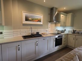 A kitchen with white cabinets countertop sink stovetop oven and kitchen appliances at Fox Howe in Thornthwaite