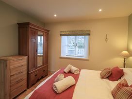 A bedroom with a wooden wardrobe a chest of drawers a bed with rolled towels and cushions and a window at Fox Howe in Thornthwaite