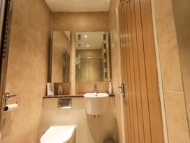 A small bathroom with a toilet a sink two mirrors and a wooden door at Fox Howe in Thornthwaite