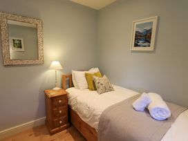 A bedroom with a single bed a bedside table with a lamp a mirror on the wall and a framed picture at Fox Howe in Thornthwaite