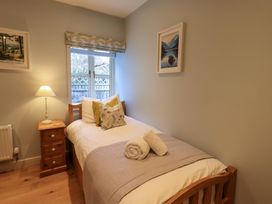 A small bedroom with a single wooden bed a bedside table with a lamp and two pictures on the walls at Fox Howe in Thornthwaite