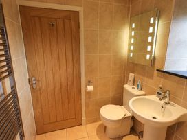A bathroom with a wooden door a toilet a pedestal sink a wall mirror and a heated towel rail at Fox Howe in Thornthwaite