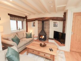 A living room with a fireplace and sofa at Jasmine Cottage in Thornthwaite