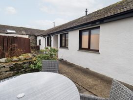 An outdoor patio area with a table and chairs at Jasmine Cottage in Thornthwaite