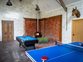 A game room with a ping pong table and a pool table near a wood stove and two wooden doors at Coach House in Llanwrtyd Wells