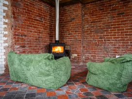 A room with exposed brick walls a wood burning stove and two green bean bag chairs on a tiled floor at Coach House in Llanwrtyd Wells