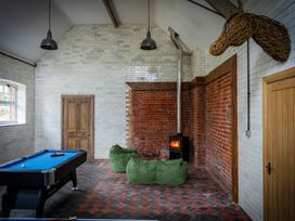 A room with a pool table two green bean bag chairs a wood stove and a horse head wall decoration at Coach House in Llanwrtyd Wells
