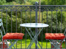 A small round table with two chairs with orange cushions on a balcony at Coach House in Llanwrtyd Wells