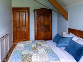 A bedroom with a bed with blue pillows a patchwork quilt a wooden door and a wooden wardrobe at Coach House in Llanwrtyd Wells