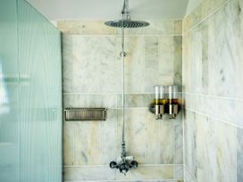 A shower area with a rain showerhead soap dispensers and a metal soap holder at Coach House in Llanwrtyd Wells