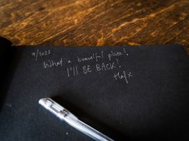 A handwritten note on black paper with a pen on a wooden surface at Coach House in Llanwrtyd Wells
