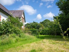 A garden with grass shrubs and small trees next to a house at Coach House in Llanwrtyd Wells
