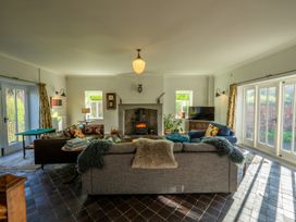 A living room with sofas around a fireplace and large windows at Coach House in Llanwrtyd Wells