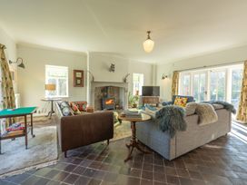 A living room with two sofas a fireplace a television and large windows at Coach House in Llanwrtyd Wells