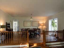 A dining room with a wooden table and chairs a sideboard with dishes framed maps on the wall and a potted plant by the window at Coach House in Llanwrtyd Wells