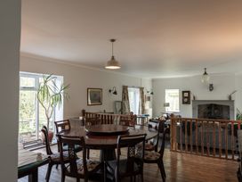 A dining area with a round wooden table and chairs next to a living room with a fireplace at Coach House in Llanwrtyd Wells