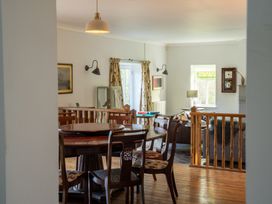 A dining area with a round wooden table and chairs next to a living room with a sofa and lamp at Coach House in Llanwrtyd Wells