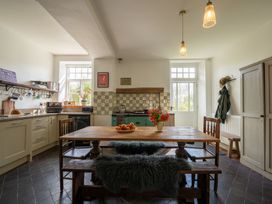 A kitchen with wooden dining table and chairs a stove and tiled backsplash at Coach House in Llanwrtyd Wells