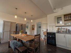 A kitchen with wooden table and chairs apples on the table pendant lights and kitchen appliances at Coach House in Llanwrtyd Wells