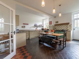 A kitchen with wooden dining table bench chairs appliances and checkered floor at Coach House in Llanwrtyd Wells