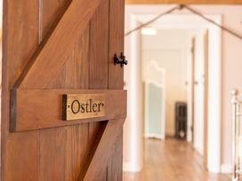 A wooden door with a sign saying Ostler looking into a hallway with wooden floors and a white room divider in the background at Coach House in Llanwrtyd Wells