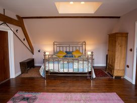 A bedroom with a metal bed frame and patchwork quilt with pillows on a wooden floor at Coach House in Llanwrtyd Wells