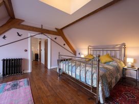 A bedroom with a metal bed frame yellow pillows rugs on wooden floor and wall decor at Coach House in Llanwrtyd Wells
