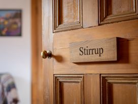 A wooden door with a brass doorknob and a sign reading Stirrup at Coach House in Llanwrtyd Wells
