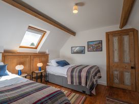 A bedroom with two single beds with plaid blankets a wooden door and a skylight window at Coach House in Llanwrtyd Wells