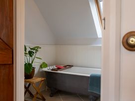 A bathroom with a clawfoot bathtub a wooden stool with a plant and a towel hanging on the tub at Coach House in Llanwrtyd Wells