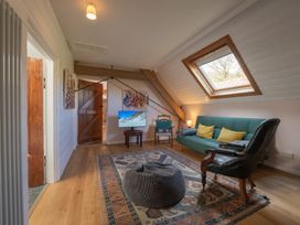 A sitting room with a skylight window a green sofa and patterned rug at Coach House in Llanwrtyd Wells