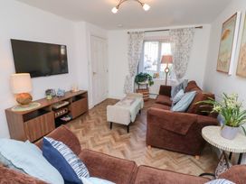A living room with brown sofas a wall-mounted TV and a wooden sideboard at Coastal Retreat in Seahouses