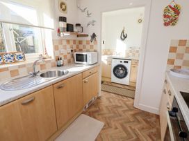 A kitchen with wooden cabinets a sink microwave and washing machine at Coastal Retreat in Seahouses