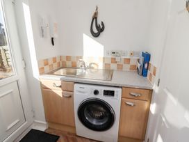 A laundry room with a washing machine sink and countertop at Coastal Retreat in Seahouses