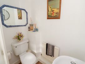 A bathroom with a toilet a sink a mirror a radiator with a towel and wall decorations at Coastal Retreat in Seahouses